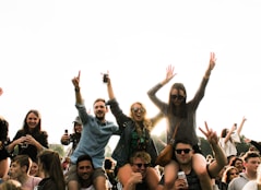 three men carrying women surrounded by many people during daytime