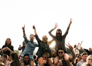 three men carrying women surrounded by many people during daytime