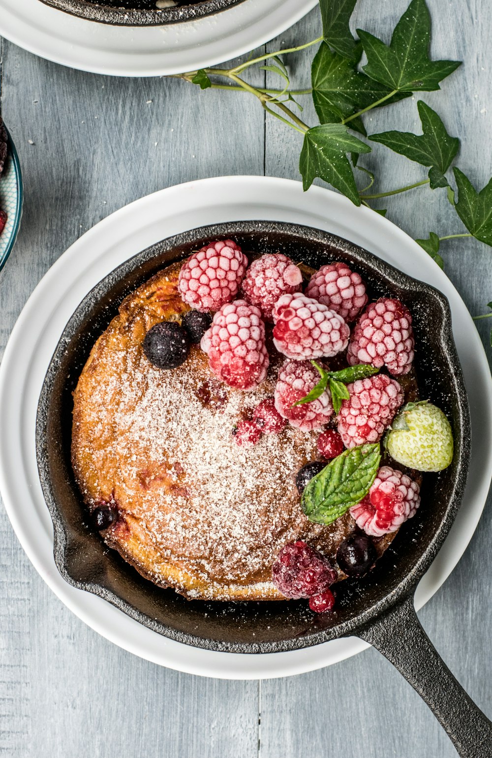 pancake with raspberry and blueberries on black cast-iron skillet