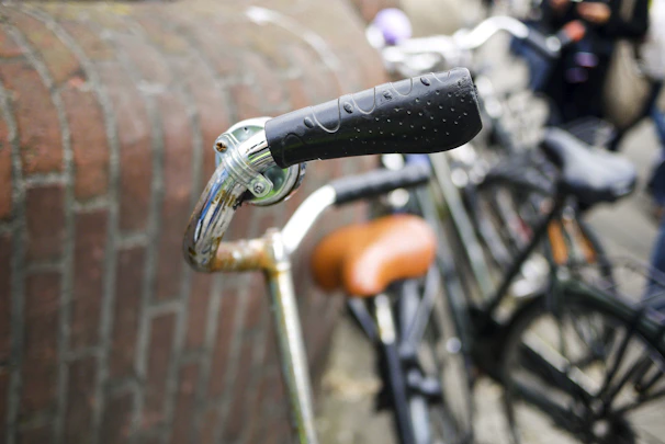Close-up of sleek bike handlebar grips in earthy tones resting on cobblestones.