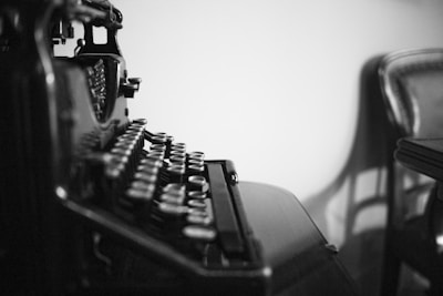 A dimly lit vintage typewriter on a dark wooden desk, casting soft shadows.
