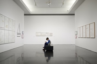 man sitting near museum painting