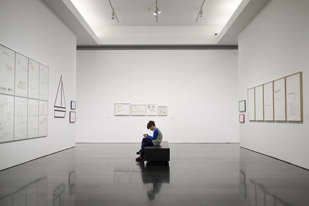 man sitting near museum painting