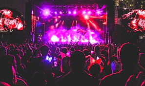 A vibrant crowd dancing under neon orange lights at a lively concert.