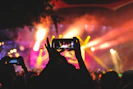 Persona tomando video desde su celular, frente al escenario en un concierto 