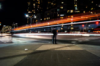 time-lapse photography of man standing beside road and bridge during daytime