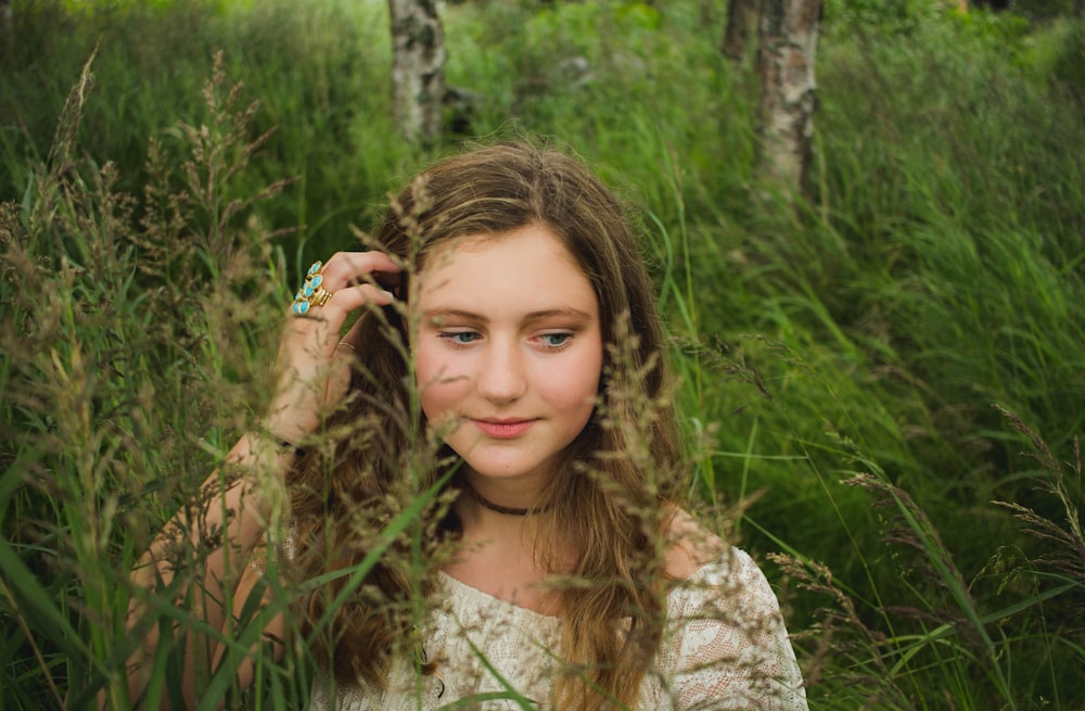 woman brushing her hair inside tall grass field