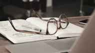 An open notebook with handwritten notes and a laptop displaying a text editing software.