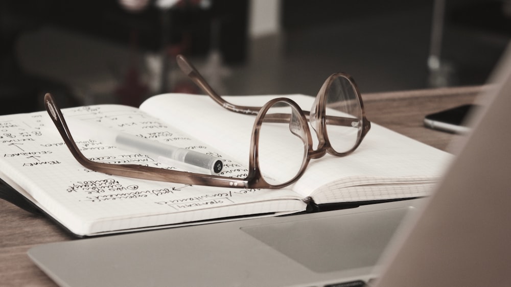 óculos com armações cinza na parte superior do notebook
