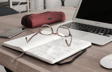 eyeglasses on book beside laptop