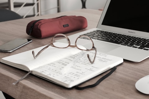 eyeglasses on book beside laptop