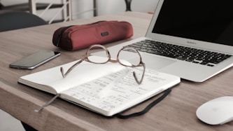 eyeglasses on book beside laptop