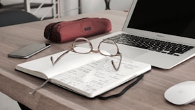 eyeglasses on book beside laptop