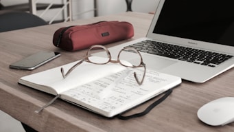 eyeglasses on book beside laptop