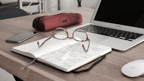 eyeglasses on book beside laptop