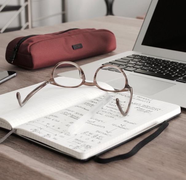 eyeglasses on book beside laptop