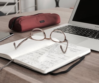 eyeglasses on book beside laptop