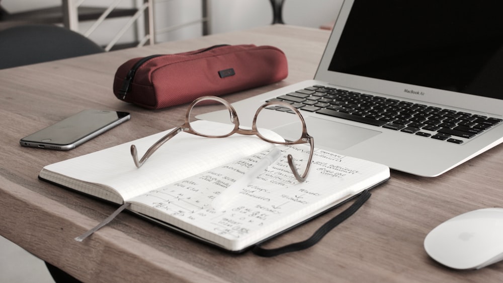 eyeglasses on book beside laptop