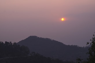 Sunset over the lush Western Ghats with mist rolling over green hills.