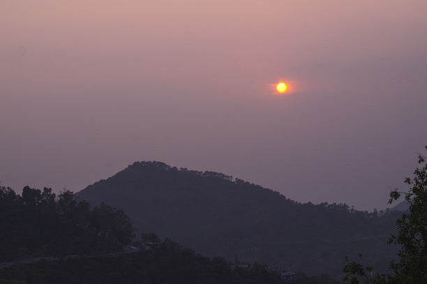 Sunset over the lush Western Ghats with mist rolling over green hills.