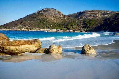 A private surf lesson in progress with calm turquoise waters and green hills in the background.