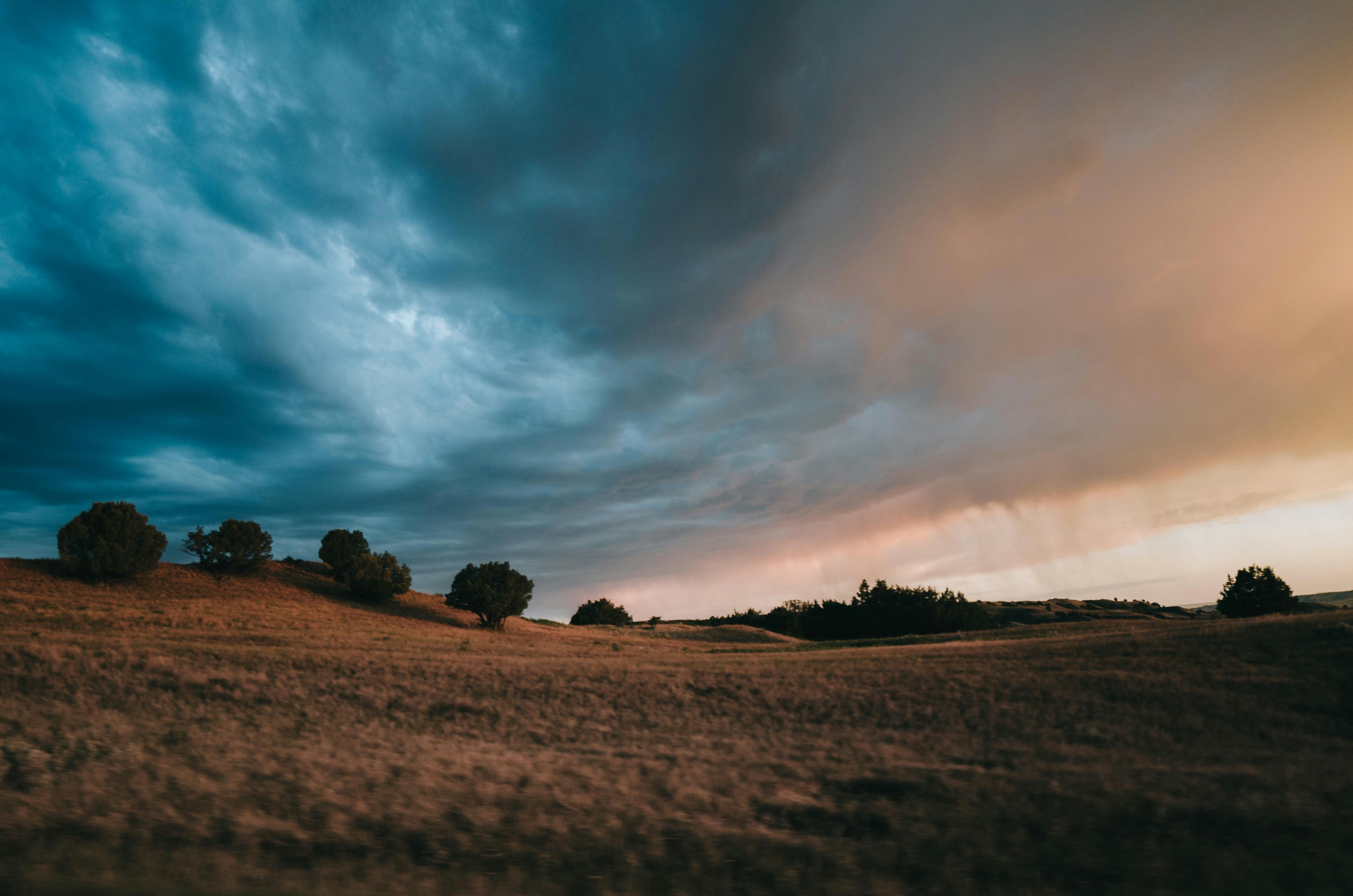 dirt field under cloudy sky during daytime