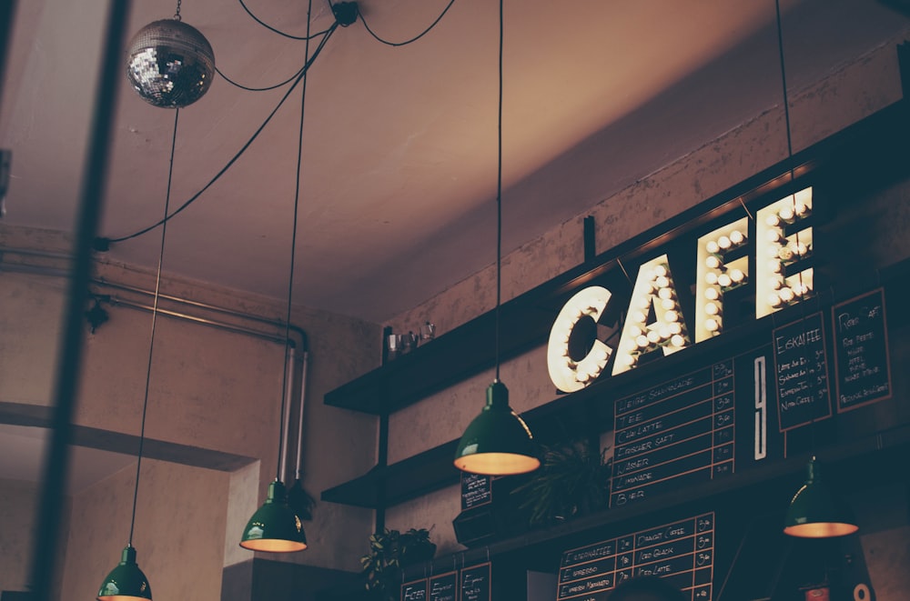 photography of cafe with LED signage and pendant lamps and menu boards