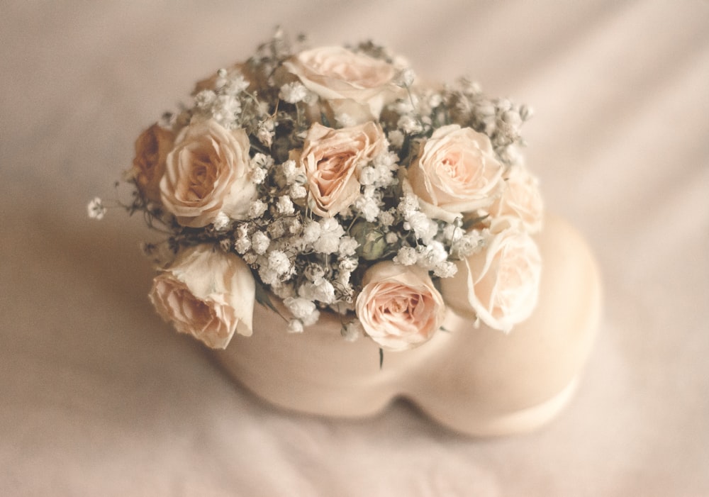 fleurs roses blanches dans un vase en céramique blanche