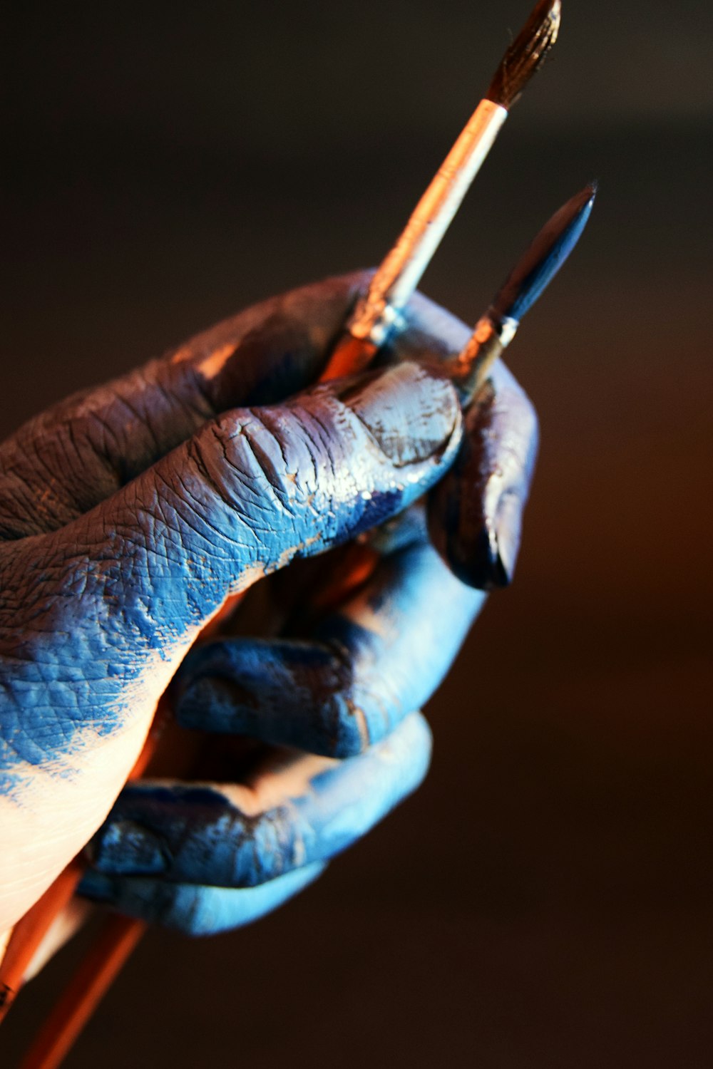 person with stained hand holding paintbrush