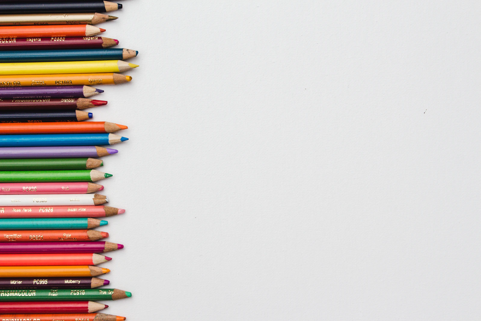 Crayons de couleur alignés sur un bureau, évoquant les devoirs et le travail scolaire à la maison