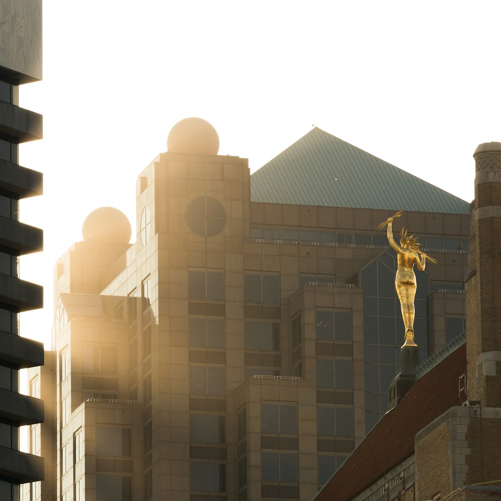 Goldene Statue in der Nähe eines braunen Betongebäudes während des Tages