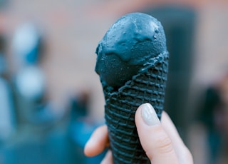 person holding black ice cream