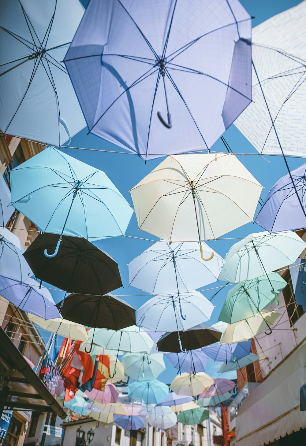 낮에는 푸른 하늘 아래 전선에 매달린 여러 가지 색의 우산