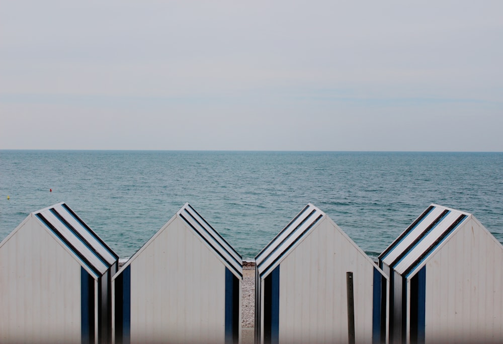 Quatre cabanons blancs et bleus sur le rivage