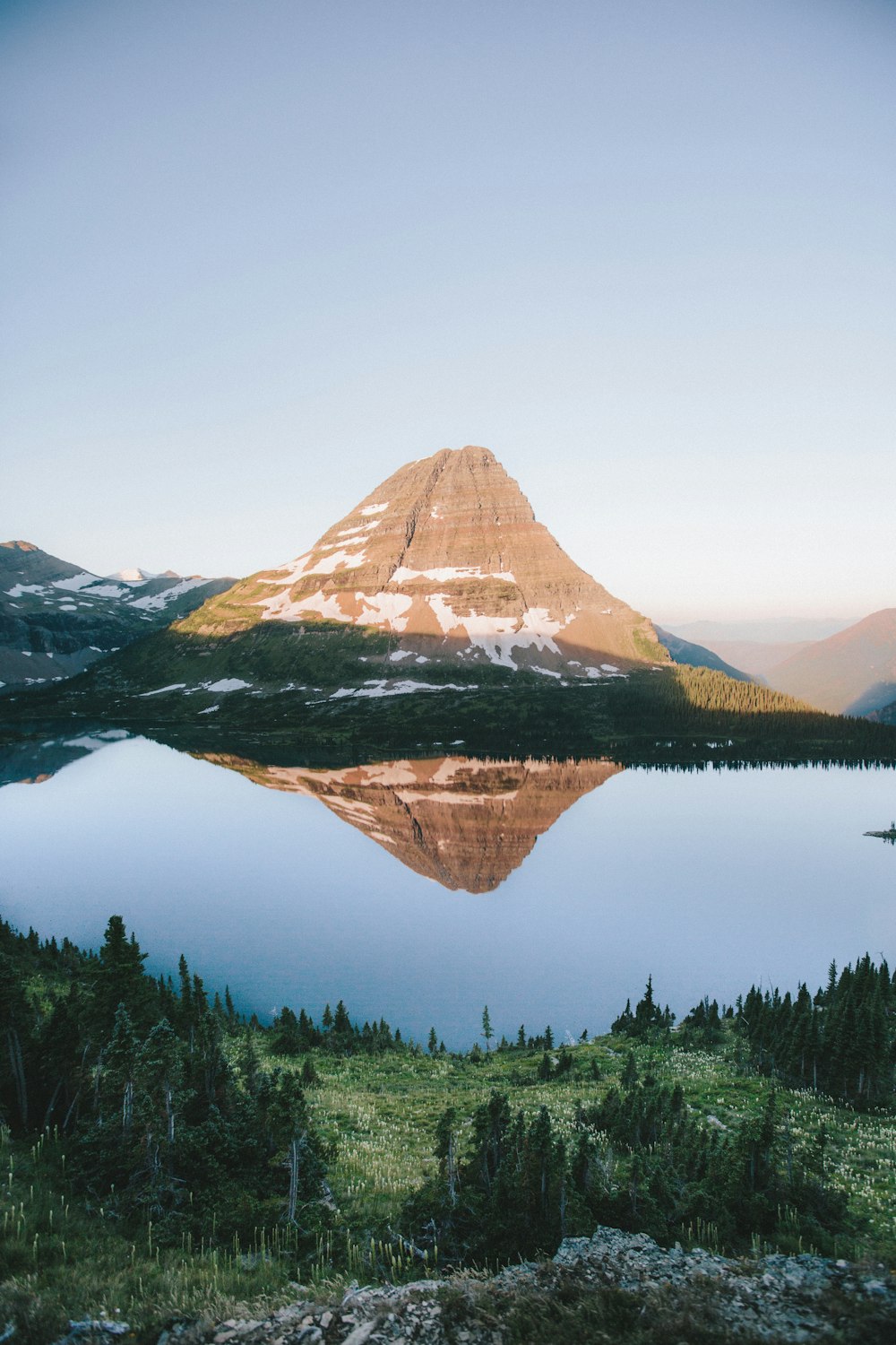 landscape photography of body of water surrounded by green trees beside mountain