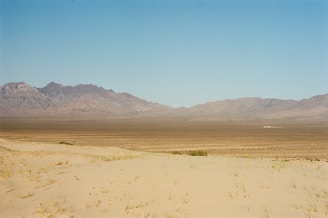 A panoramic view of the endless Gobi Desert under a clear blue sky with a traditional Mongolian ger in the foreground.