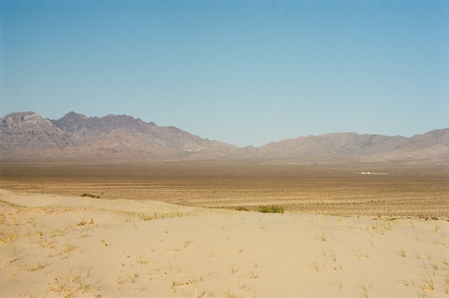 A panoramic view of the endless Gobi Desert under a clear blue sky with a traditional Mongolian ger in the foreground.