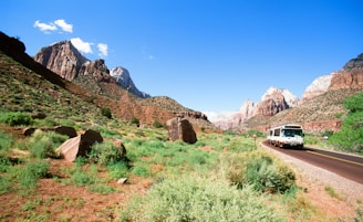 A scenic view of Oman's rugged mountains with a winding road and a tour bus.