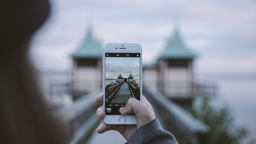 Mujer tomando foto de arquitectura interesante en iPhone con fondo fuera de foco, Persborg