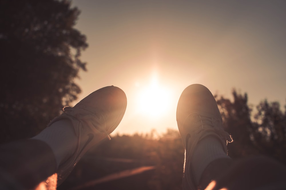 person wearing white Nike lace-up sneakers during golden hour