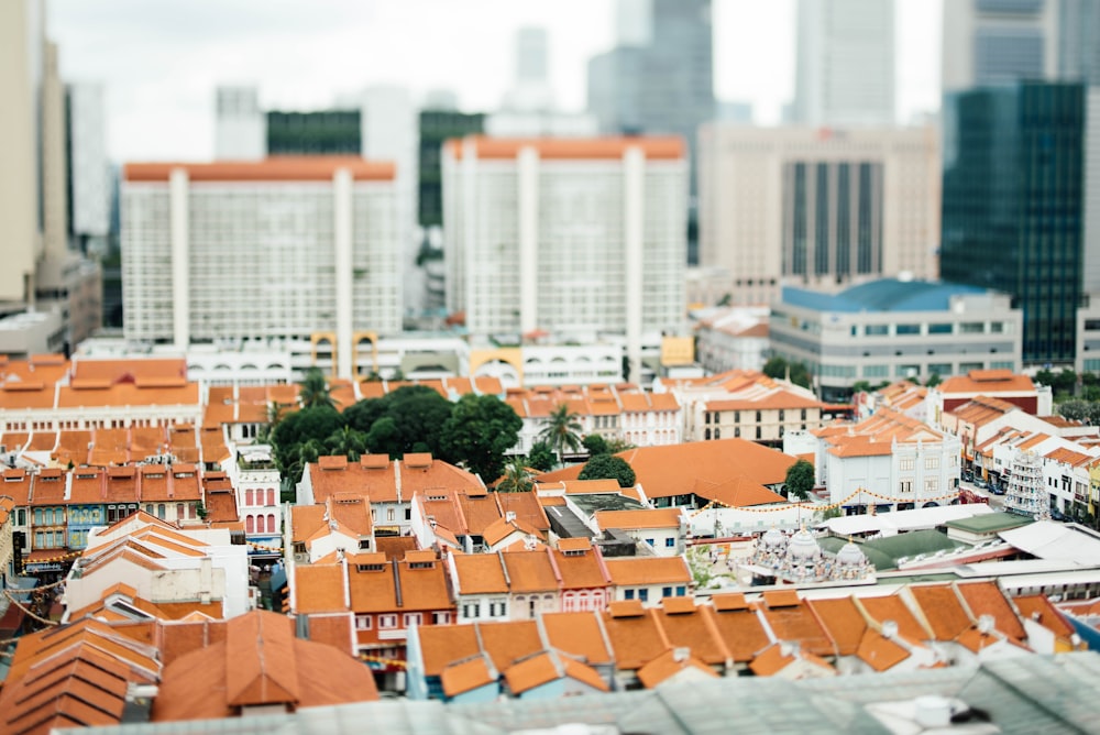 Photographie inclinable et décalée de maisons blanches et oranges entourées d’immeubles de grande hauteur pendant la journée