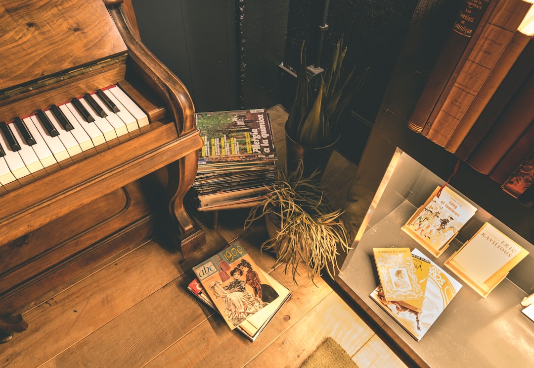 brown wooden upright piano beside black wooden cabinet