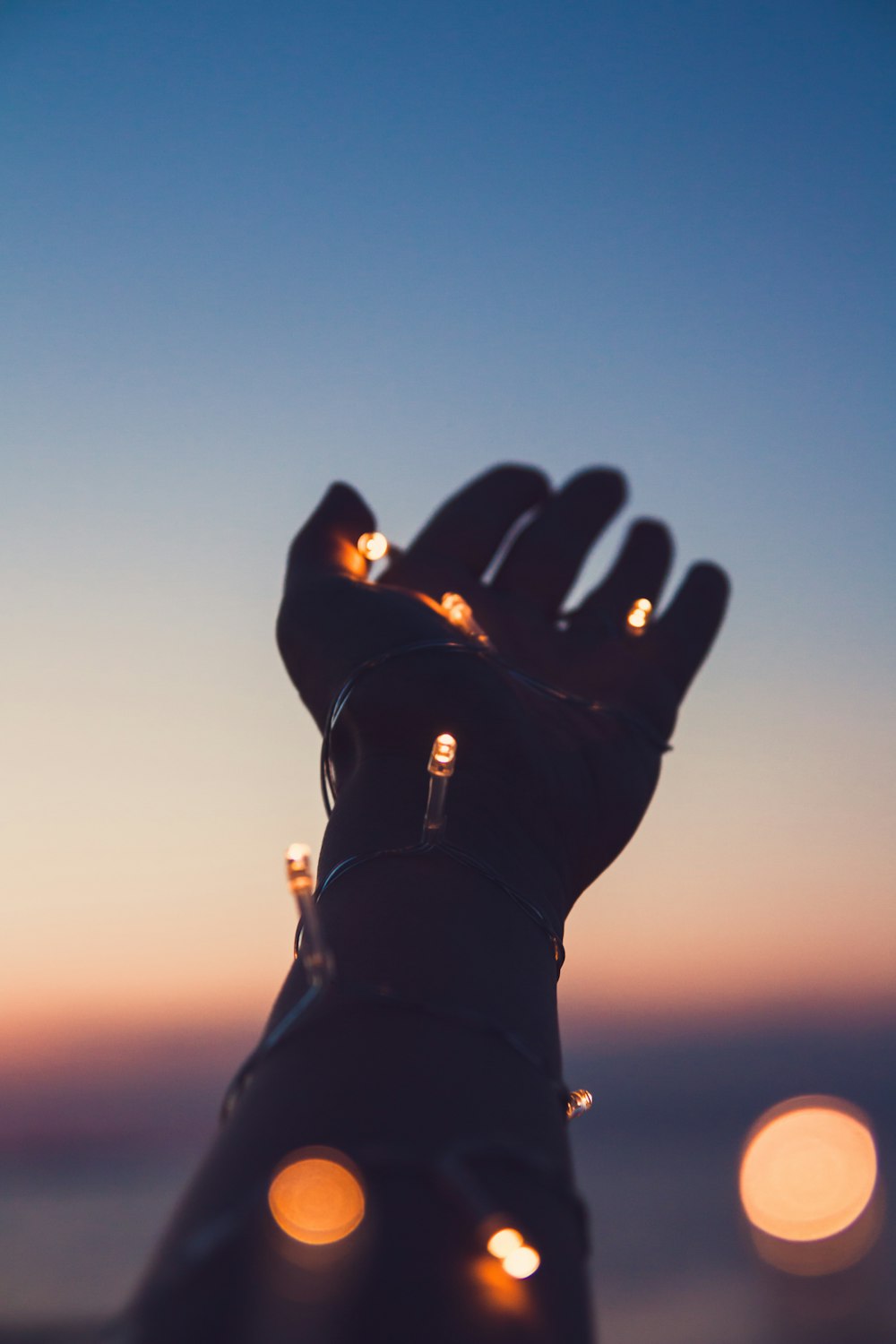 person showing left hand with string lights