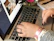 Close-up of hands typing on a keyboard with a purple notebook and lavender flowers nearby.