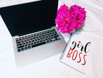 A confident woman working on her laptop with a Bible and notebook nearby, symbolizing faith and business.