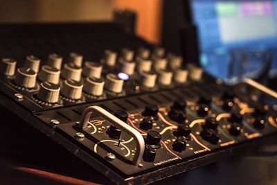 Close-up of a microphone and mixing console in a warm-lit studio.