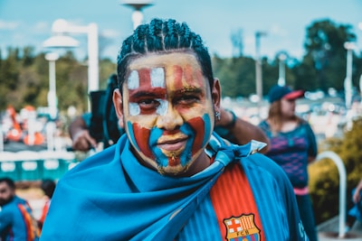 Close-up of a fan wearing team apparel and face paint at a basketball game.