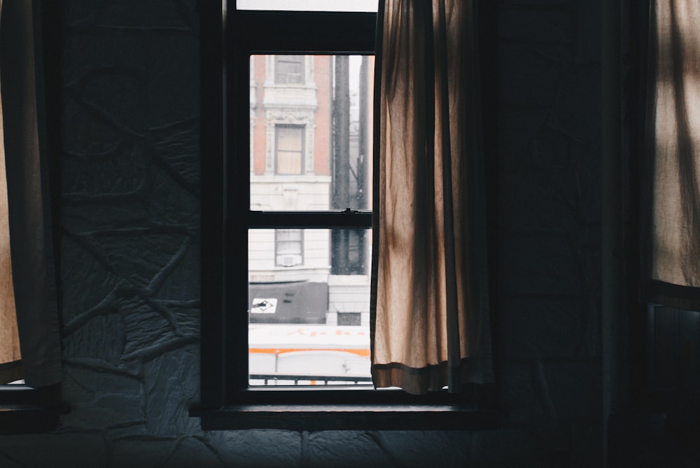 brown window curtain beside black wooden sash window