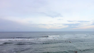 Surfers and stand up paddleboarders connecting with the ocean under a bright sky.
