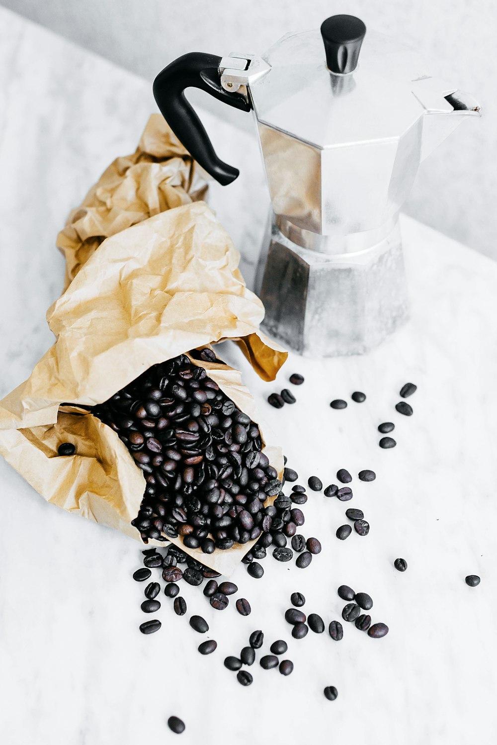 Schwarze Kaffeebohnen und graue Mokkakanne